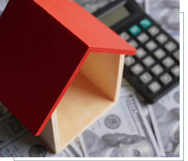 Small wooden house model with calculator and dollar bills representing real estate finance.